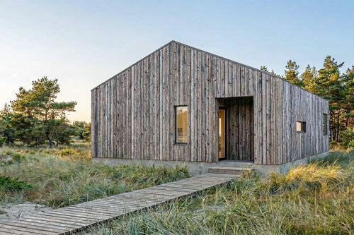 Wooden cabin in a natural setting with trees and grass.